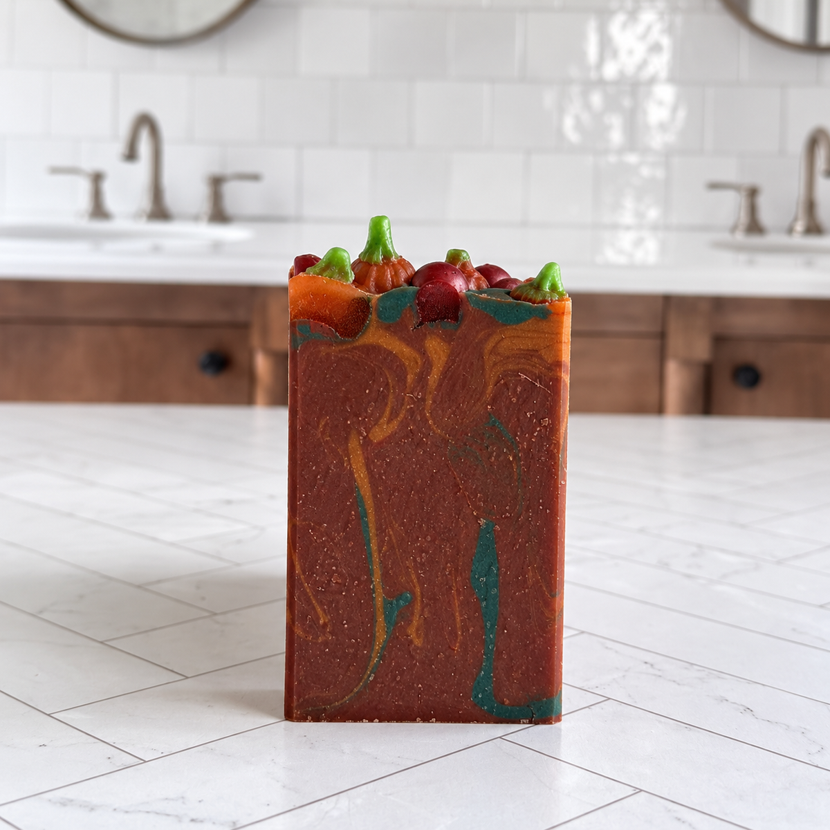 A rectangular handmade soap bar with a terracotta orange base, marbled orange and teal swirls, and small decorative pepperoni and green pepper accents on top, standing on a white tiled countertop in a kitchen setting.