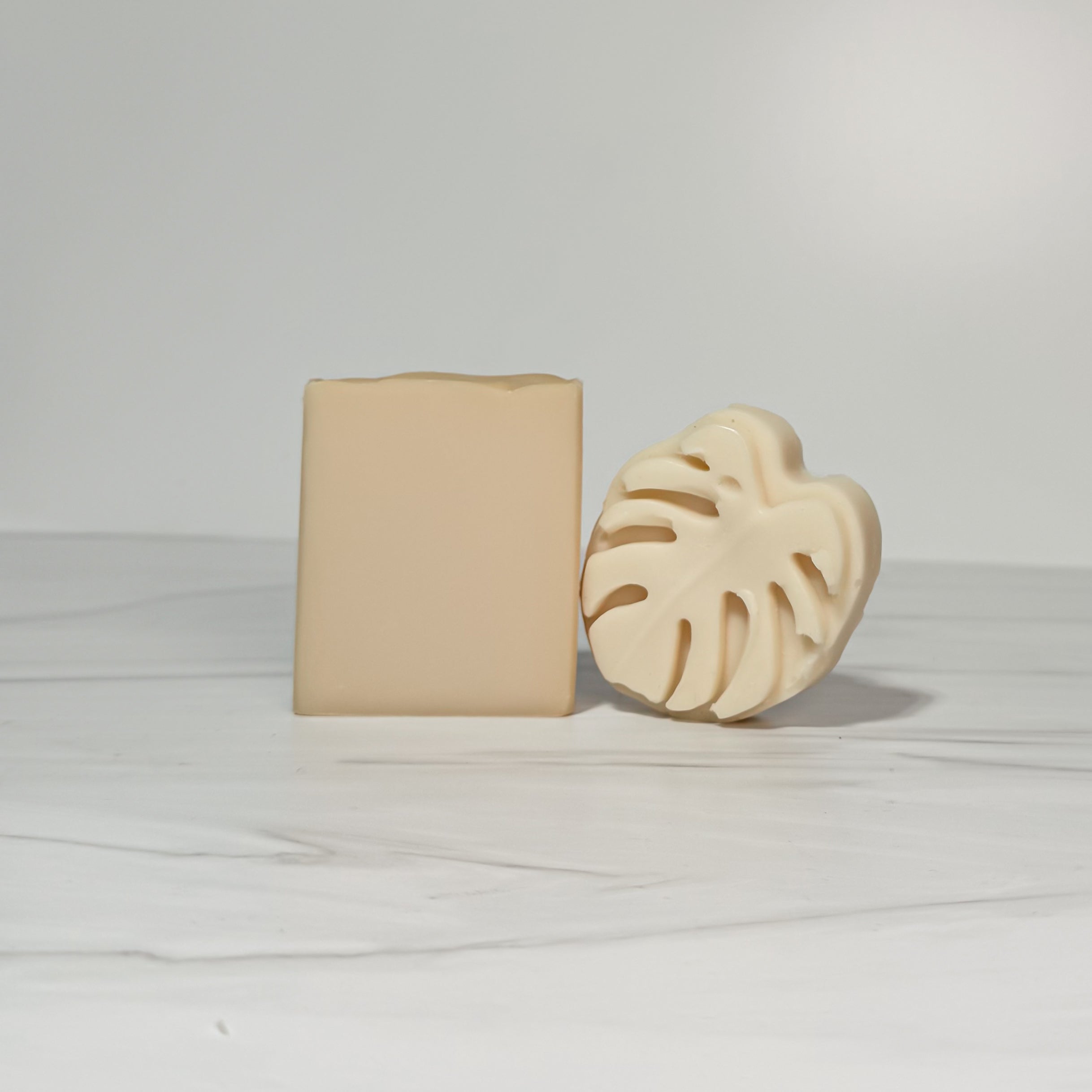 Two beige soap bars on a light gray background