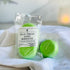 one package of just breath shower steamers are shown leaning on a white cloth covered box, this shows the pack of 2 and the label. next to this is a single shower steamer still sealed in biodegradable film for freshness.