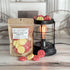apple ginger spritz wax melt bag is full and standing next to a rustic farmhouse type burner that is on and filled with the pieces of wax in the shape of cute waffles - pink and yellow!. there are also a waffle pieces on the table in front of both to show the size and color of the pieces