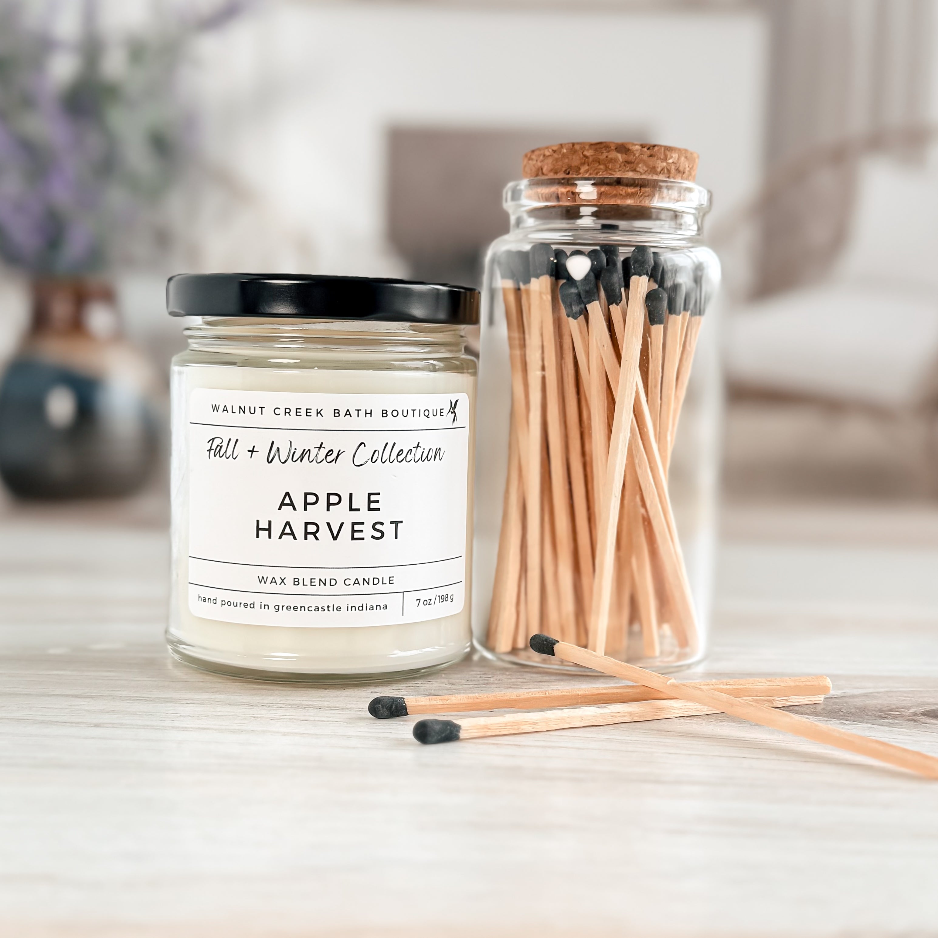 Apple Harvest candle and matches on a wooden surface with a blurred background