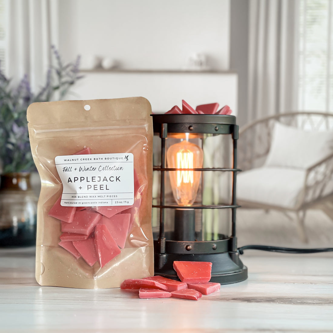 applejack and peel wax melt bag next to lit burner. there are wax melts on the table scattered about to shoe the pieces - these are red brittle type pieces