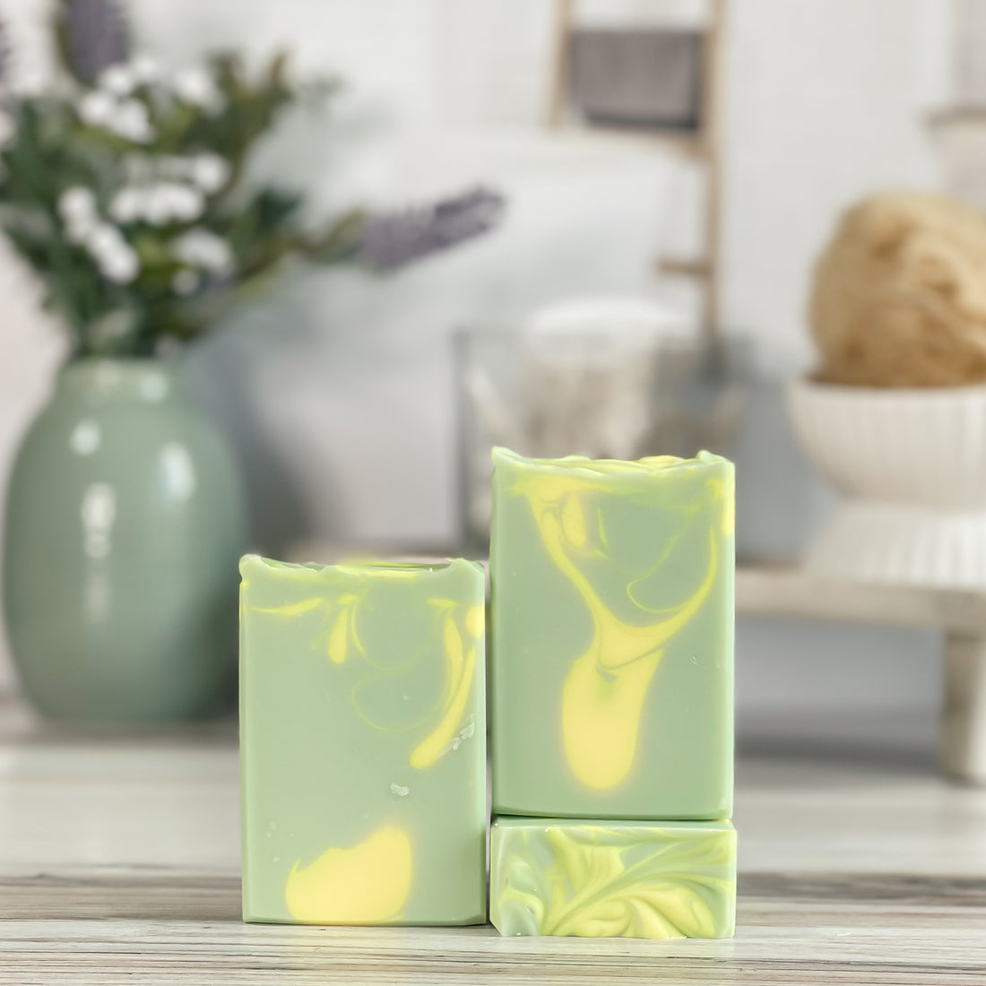 Green and yellow marbled soap bars on a wooden surface with a blurred background
