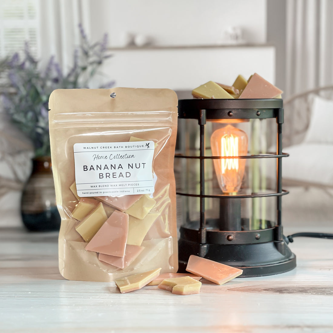 banana nut bread wax melt bag next to lit burner. there are wax melts on the table scattered about to shoe the pieces - these are tan and brown two tone brittle type pieces