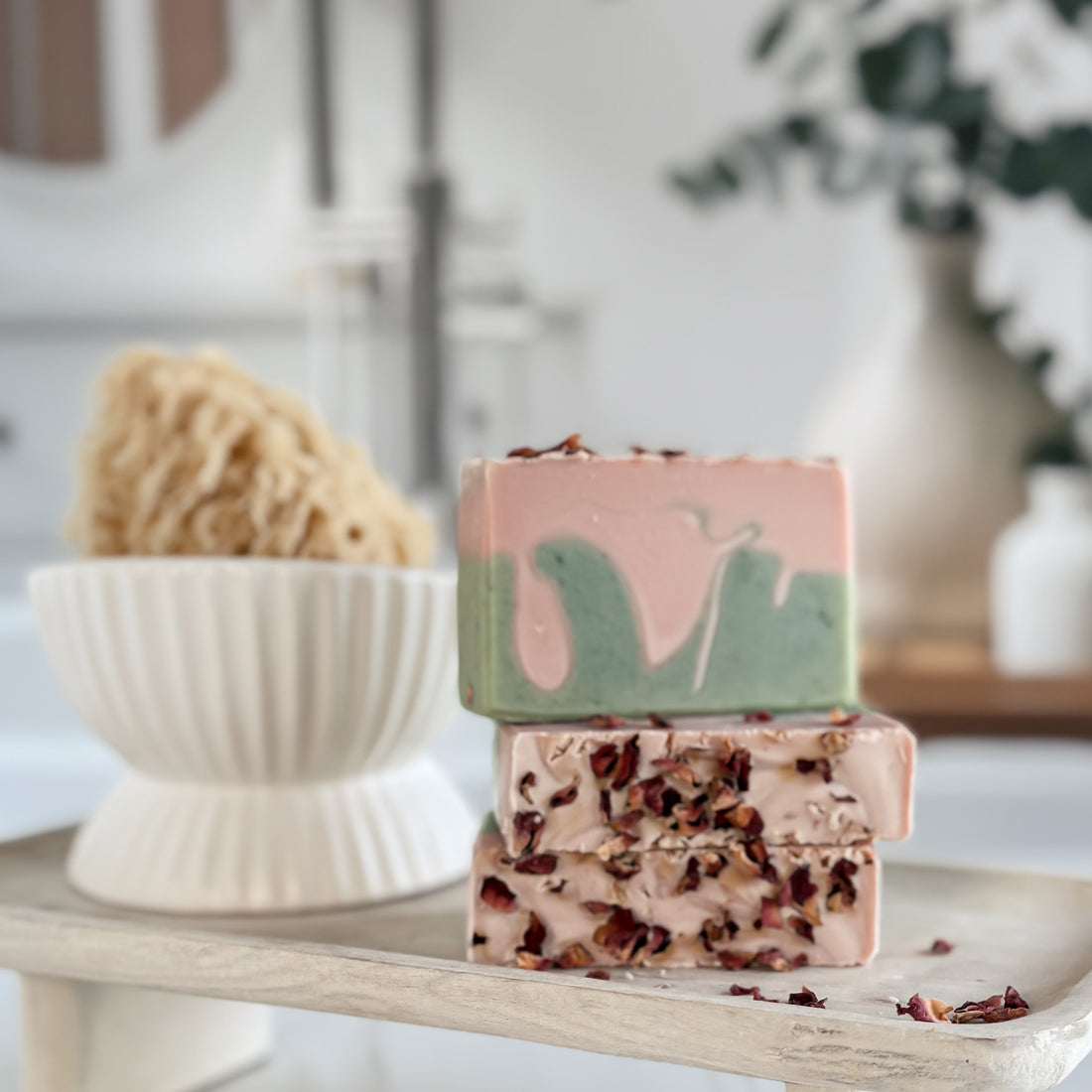 Stack of colorful soap bars with natural ingredients on a wooden surface.