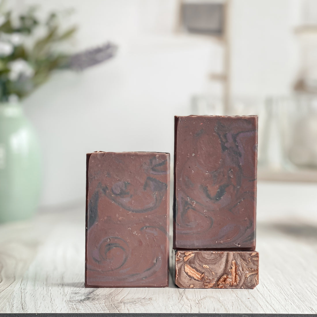 Three marbled brown soap bars on a light surface with a blurred background
