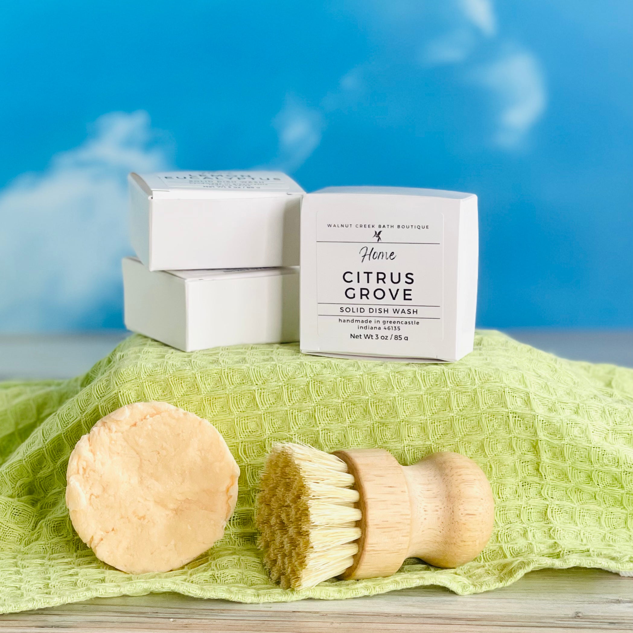 stacks of citrus grove dish wash refills on a green covered riser with an unboxed one with the brush below them