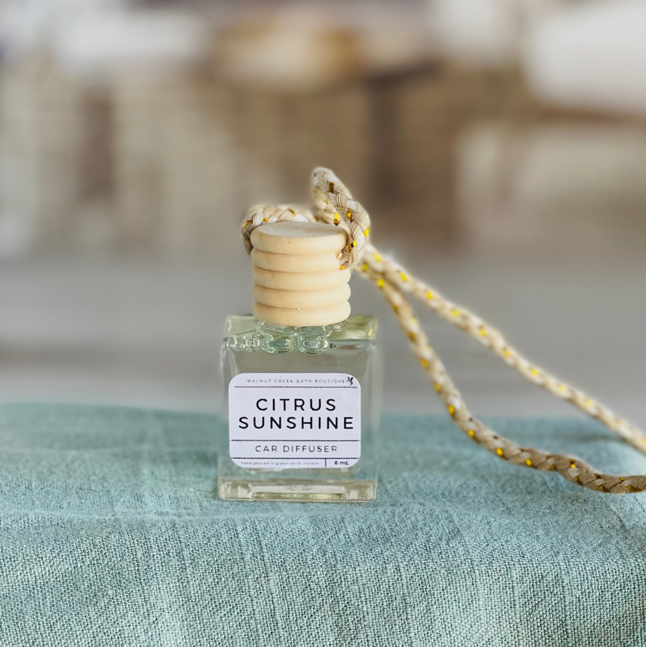 citrus sunshine car diffuser shown up close on a green cloth in front of a wicker basket.
