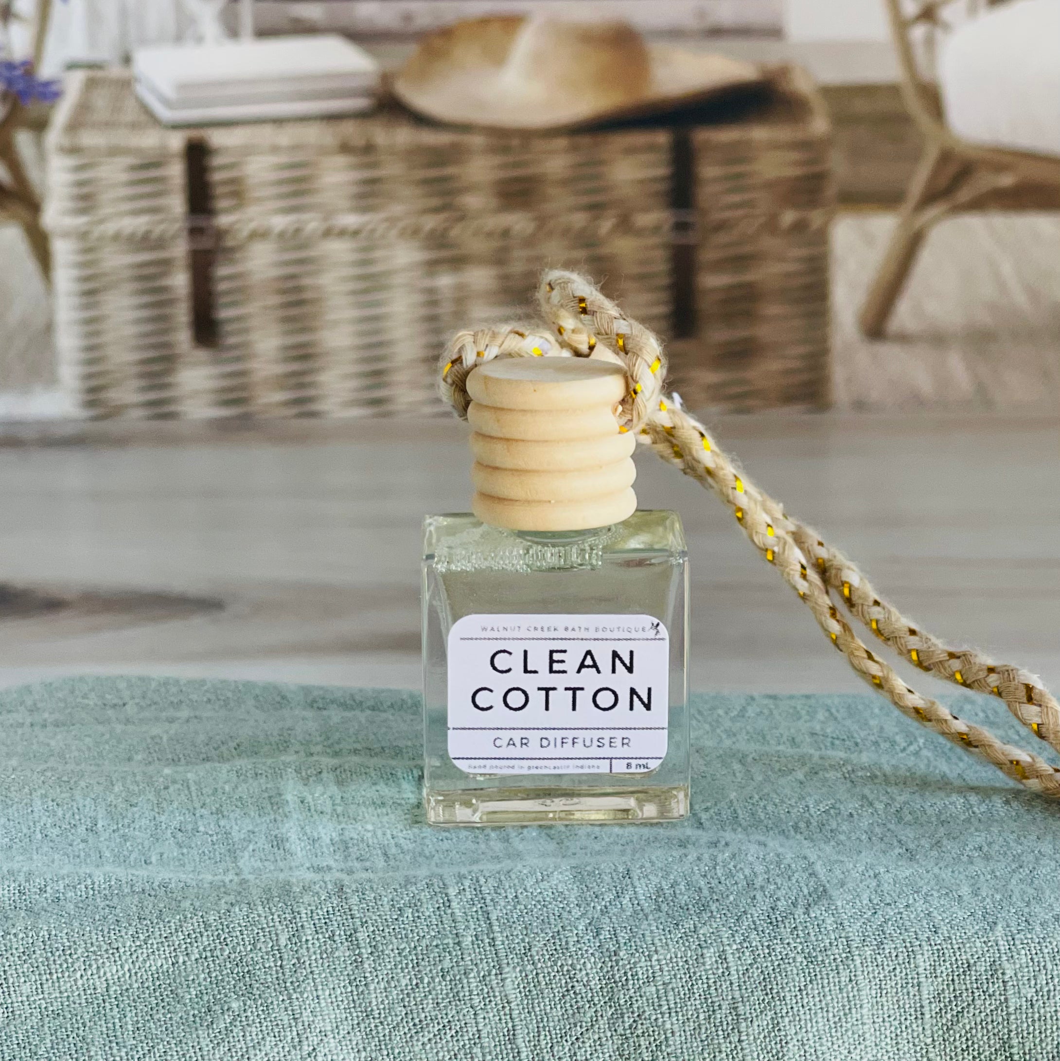 clean cotton car diffuser shown up close on a green cloth in front of a wicker basket.