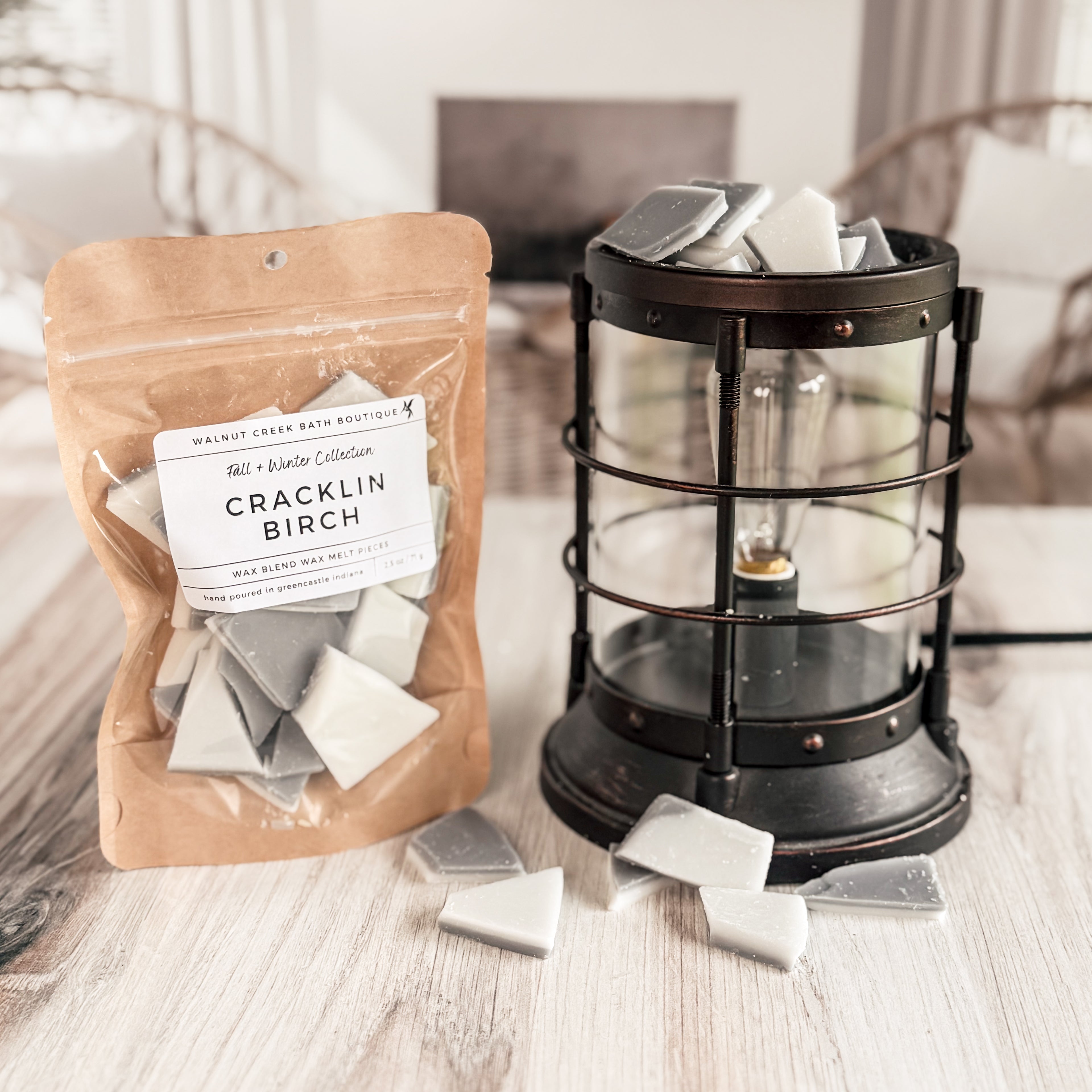 Packaged Cracklin Birch wax melts next to a lantern on a wooden surface.