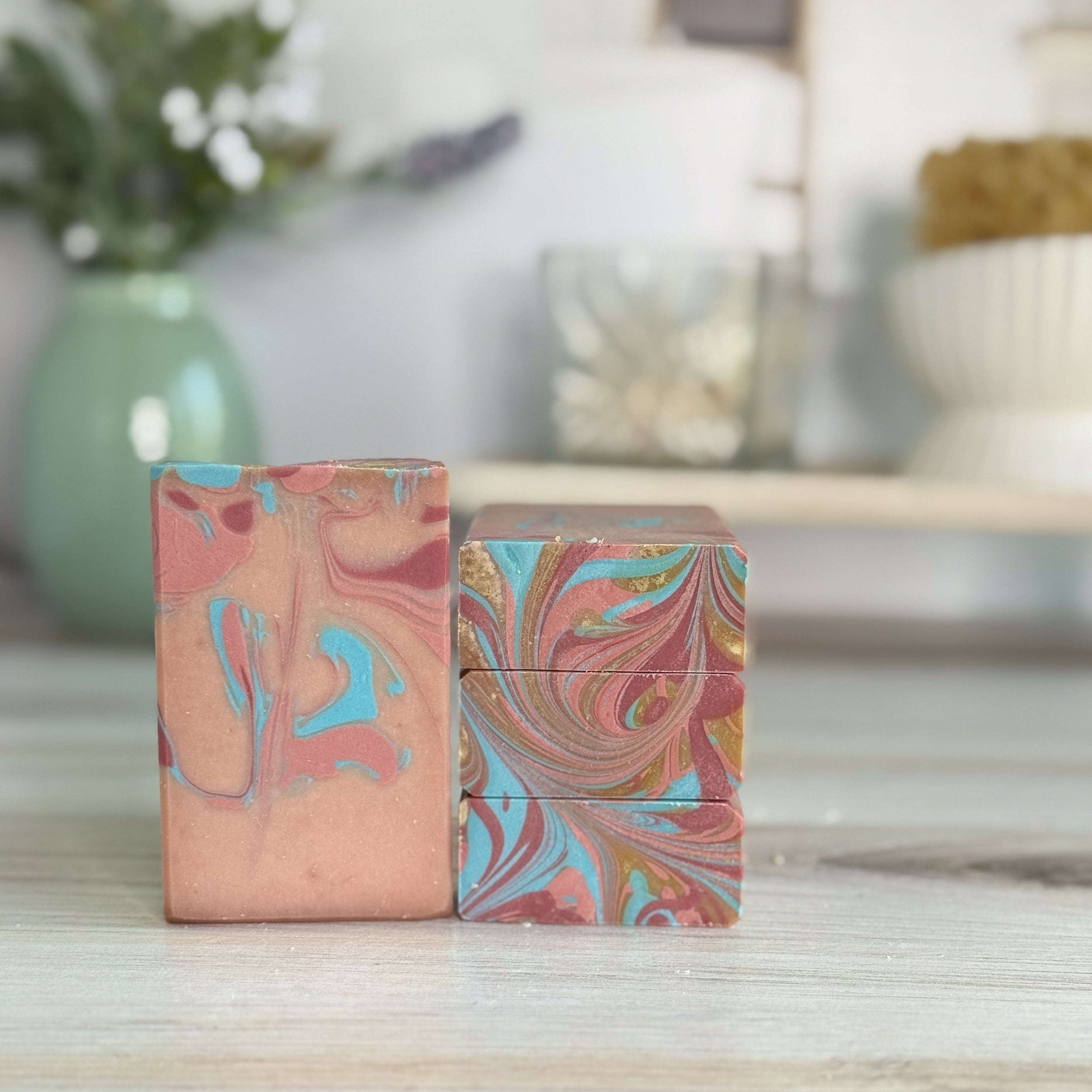 Two marbled patterned soaps on a wooden surface with a blurred background