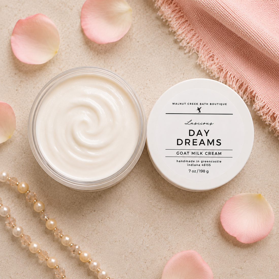 Day Dreams goat milk cream jar with lid on a beige surface with pink petals and a towel.