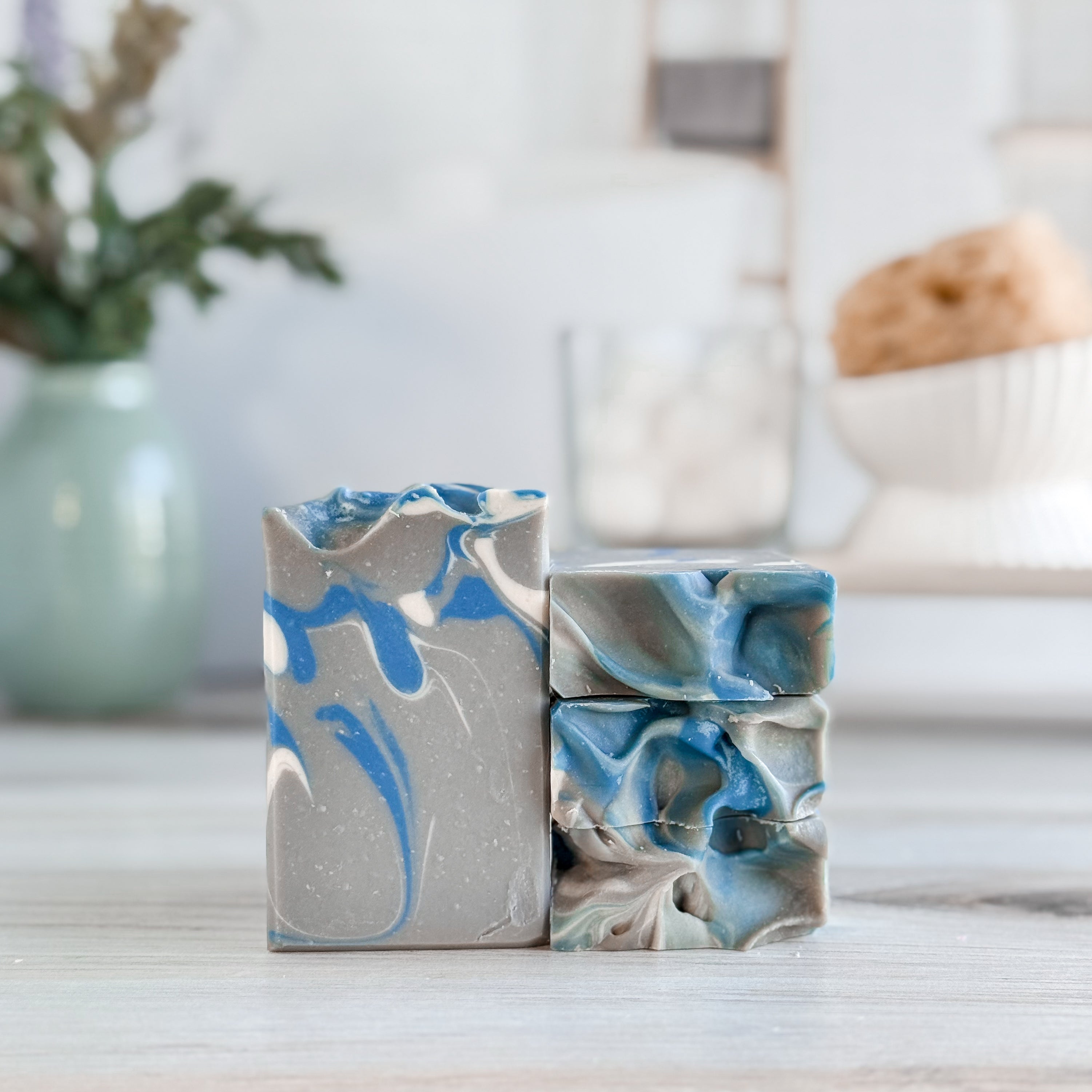 Marbled blue and gray soap bars on a wooden surface with a blurred indoor background