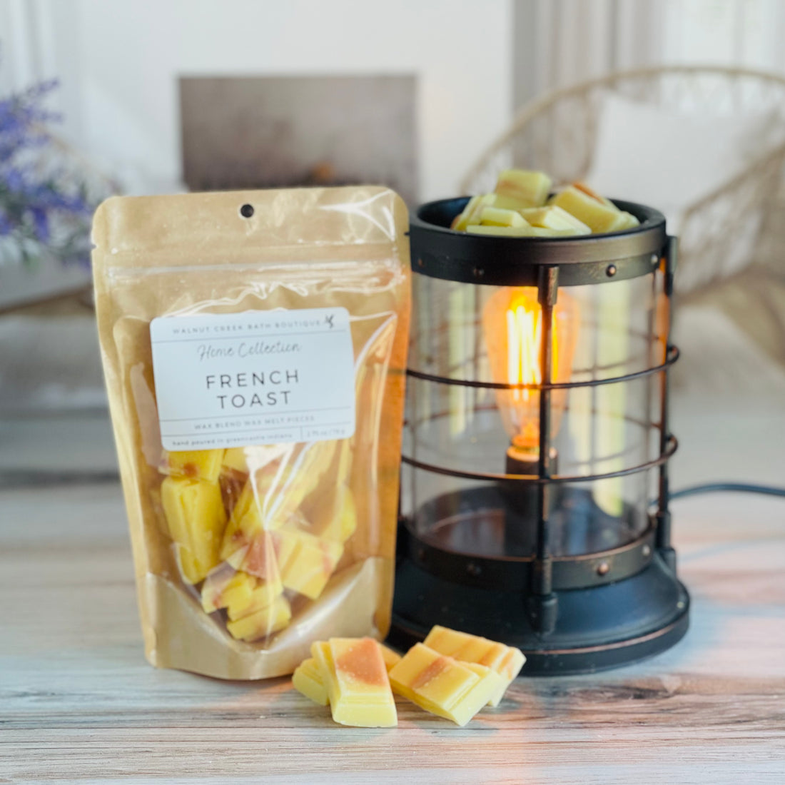 french toast wax melt bag is full and standing next to a rustic farmhouse type burner that is on and filled with the yellow/orange snap bar pieces of wax. there are also a few pieces of the snapped bar on the table in front of both to show the size and color of the pieces
