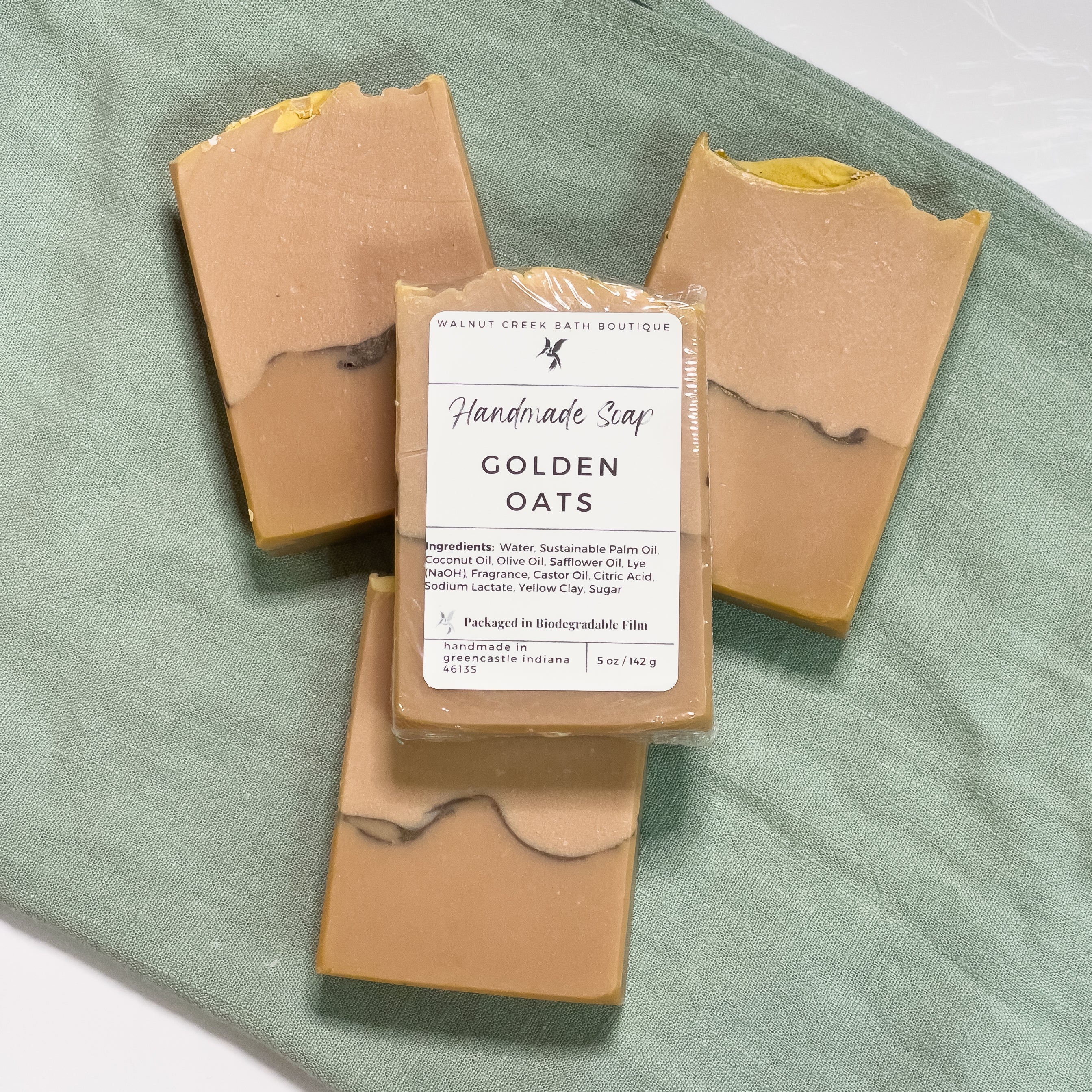 3 golden oats are laying flat on a green cloth with another on top of them showing the label.