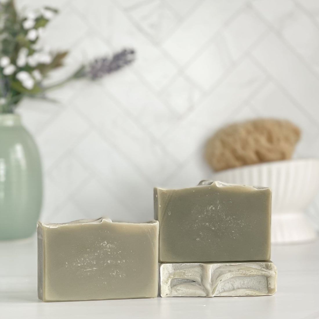one green oasis soap is standing next to one laying flat to show the top and another standing on the flat one to show more of the soap colors