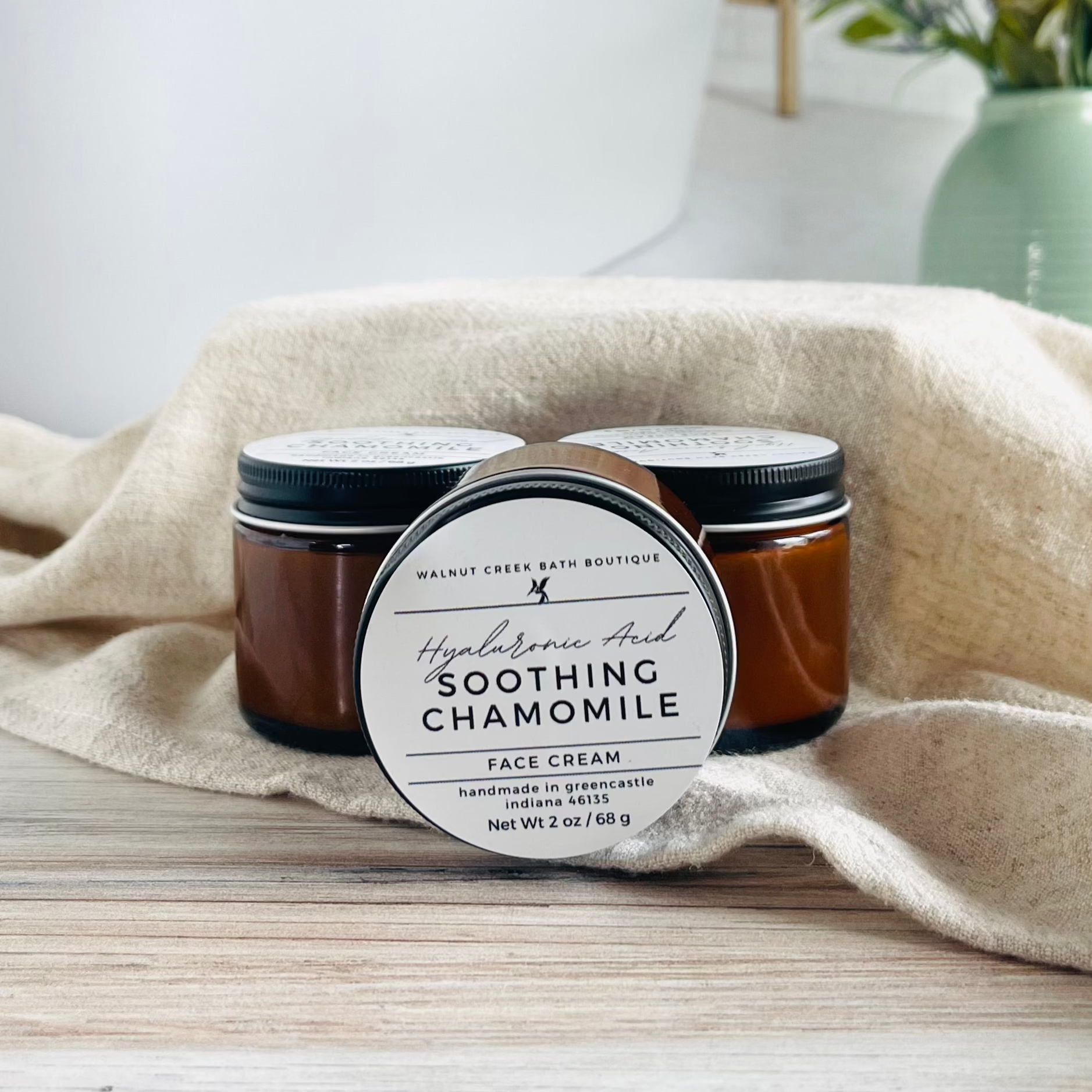 hyaluronic face cream with one on side facing and two others in the background sitting upright to show amber glass jar