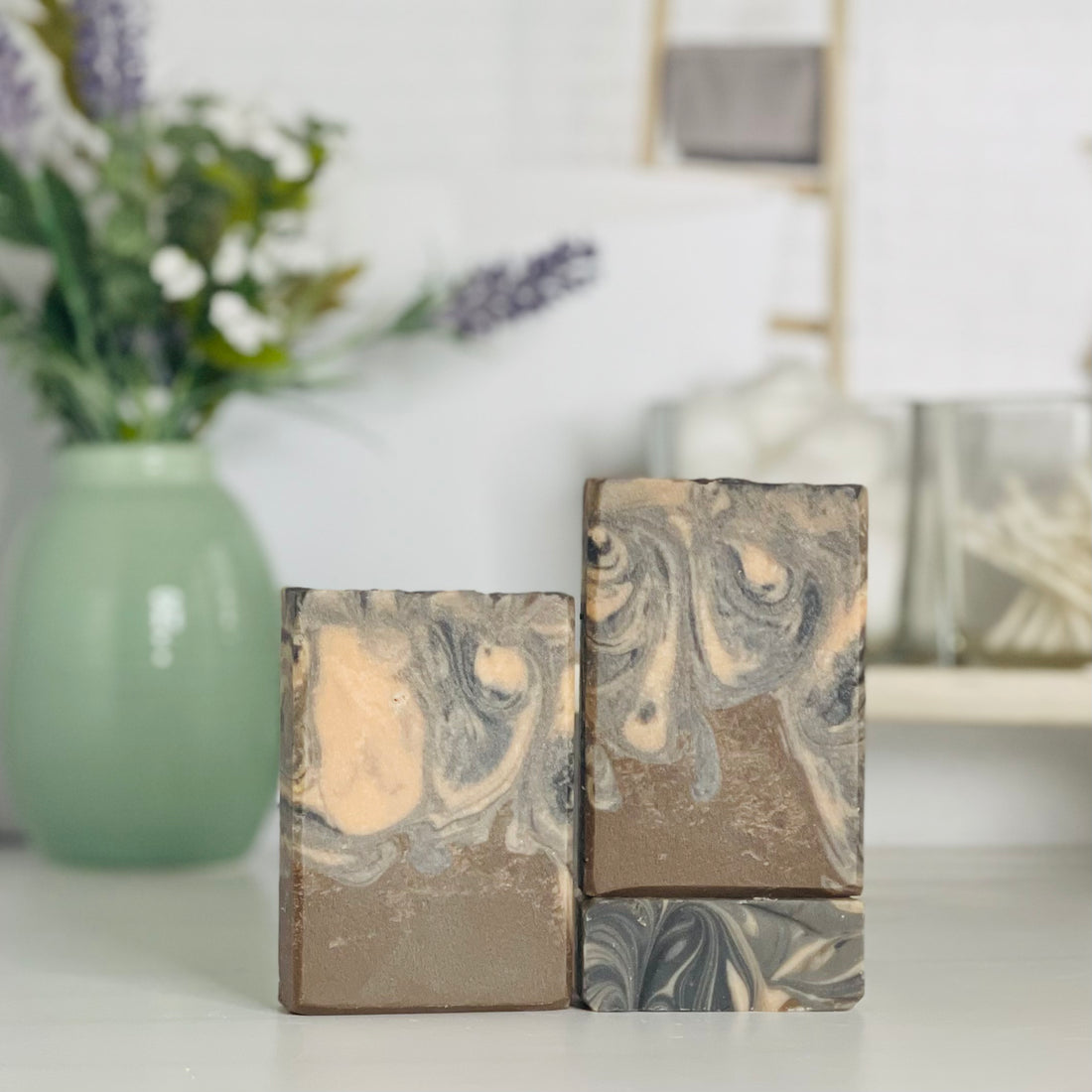 one indian sandalwood soap is standing next to one laying flat to show the top and another standing on the flat one to show more of the soap colors