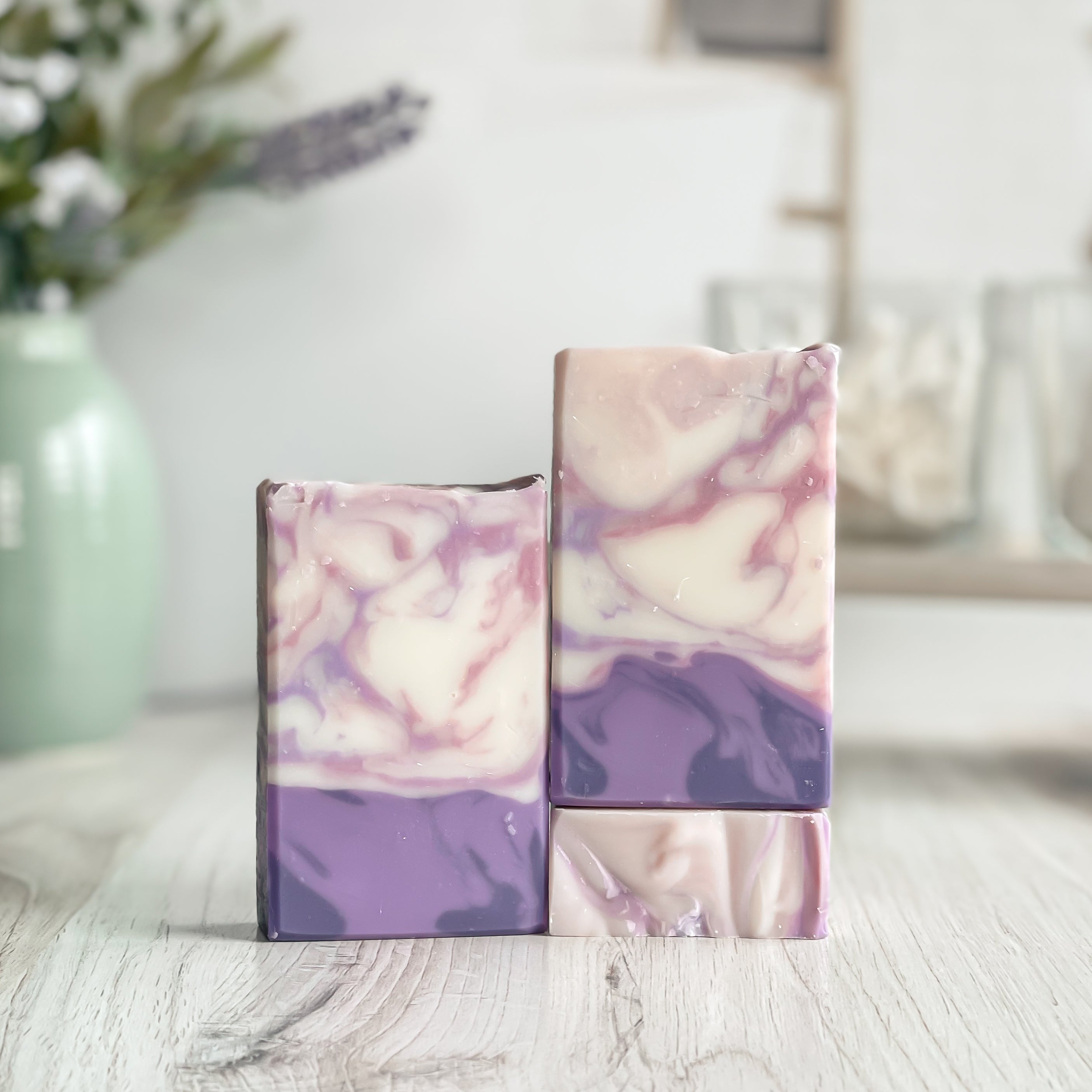 Two marbled soap bars with pink and purple hues on a wooden surface.