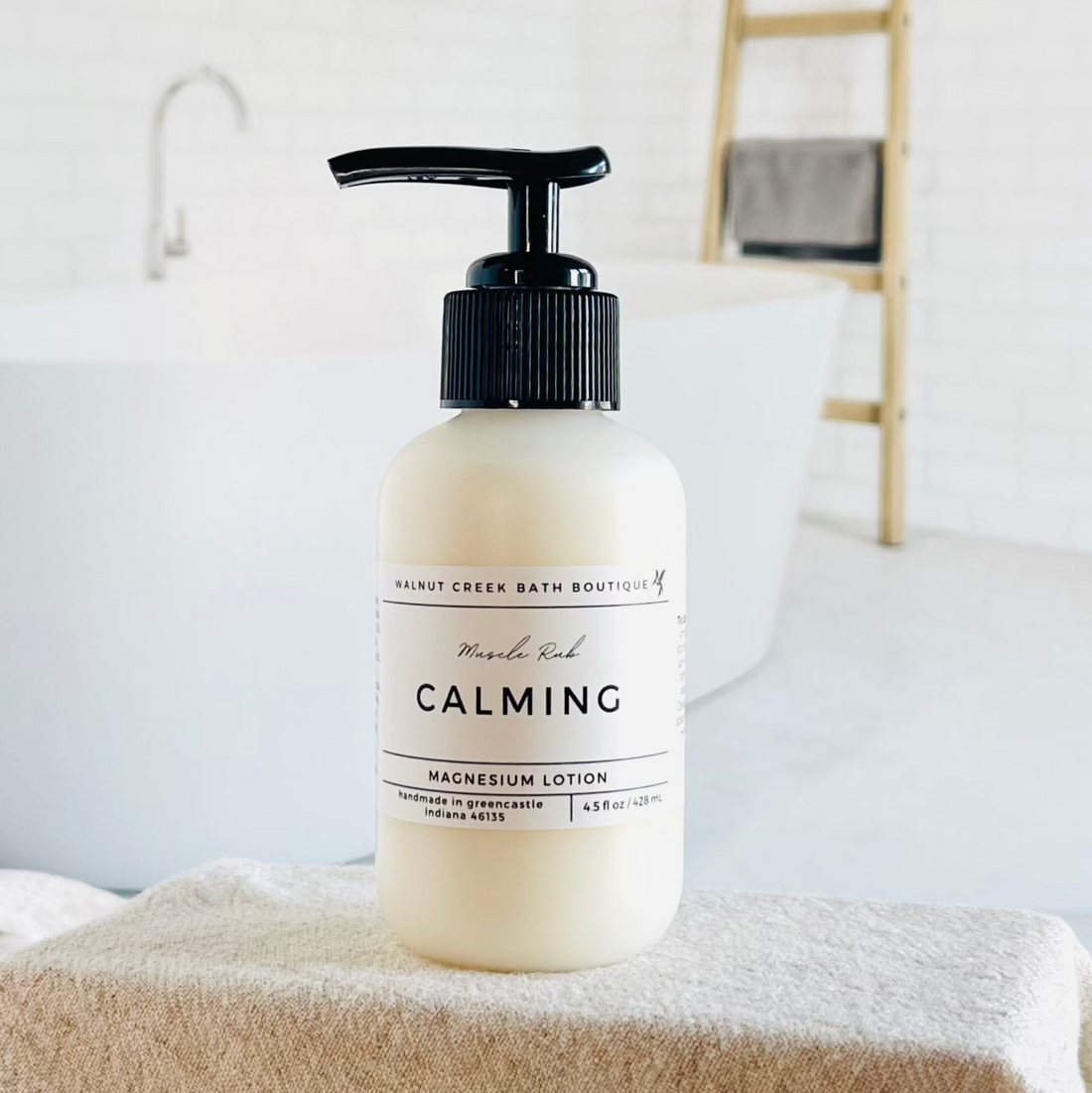 magnesium lotion is in an opaque bottle with a black pump. it is sitting in front of a very pretty bathtub.