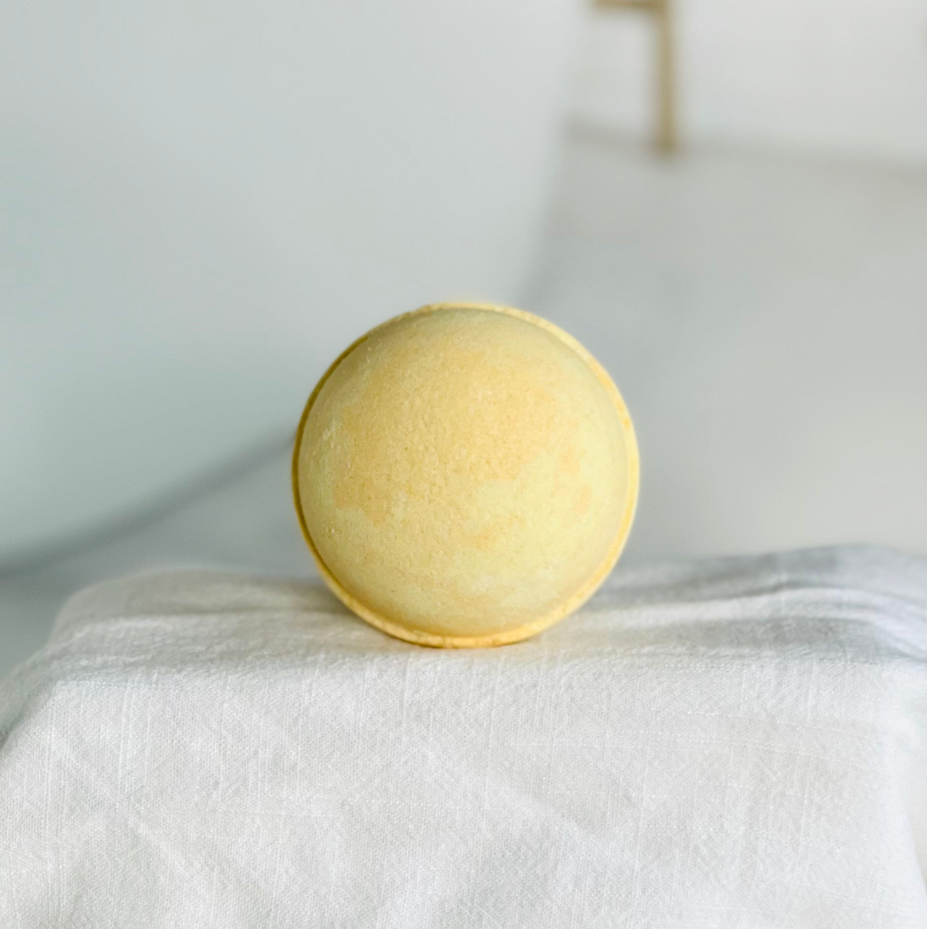 our mango papaya bath bomb has yellow and orange swirls. this close up view shows these off while it is sitting on a white cloth cover riser