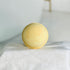 our mango papaya bath bomb has yellow and orange swirls. this close up view shows these off while it is sitting on a white cloth cover riser