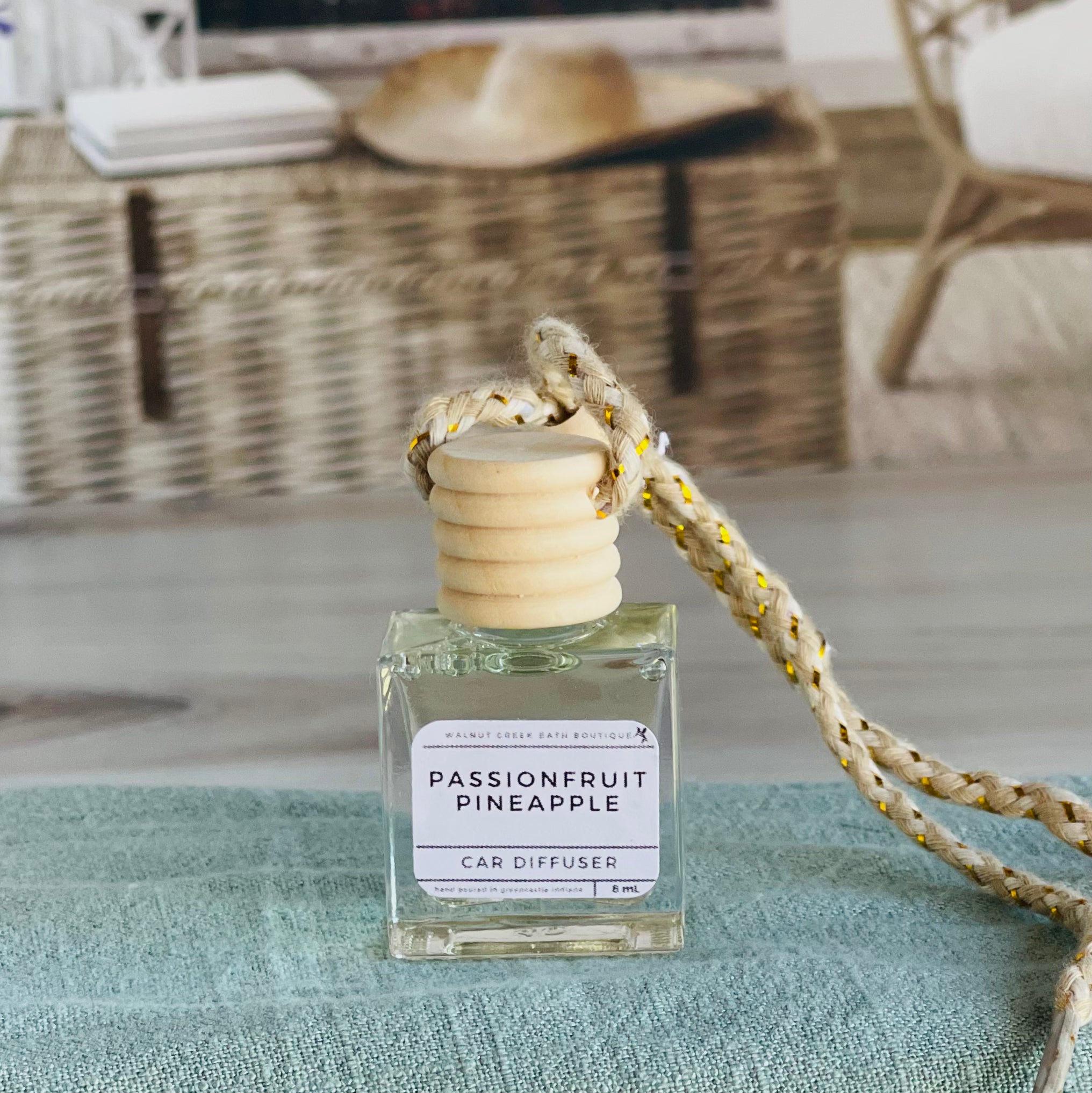 passionfruit pineapple car diffuser shown up close on a green cloth in front of a wicker basket.