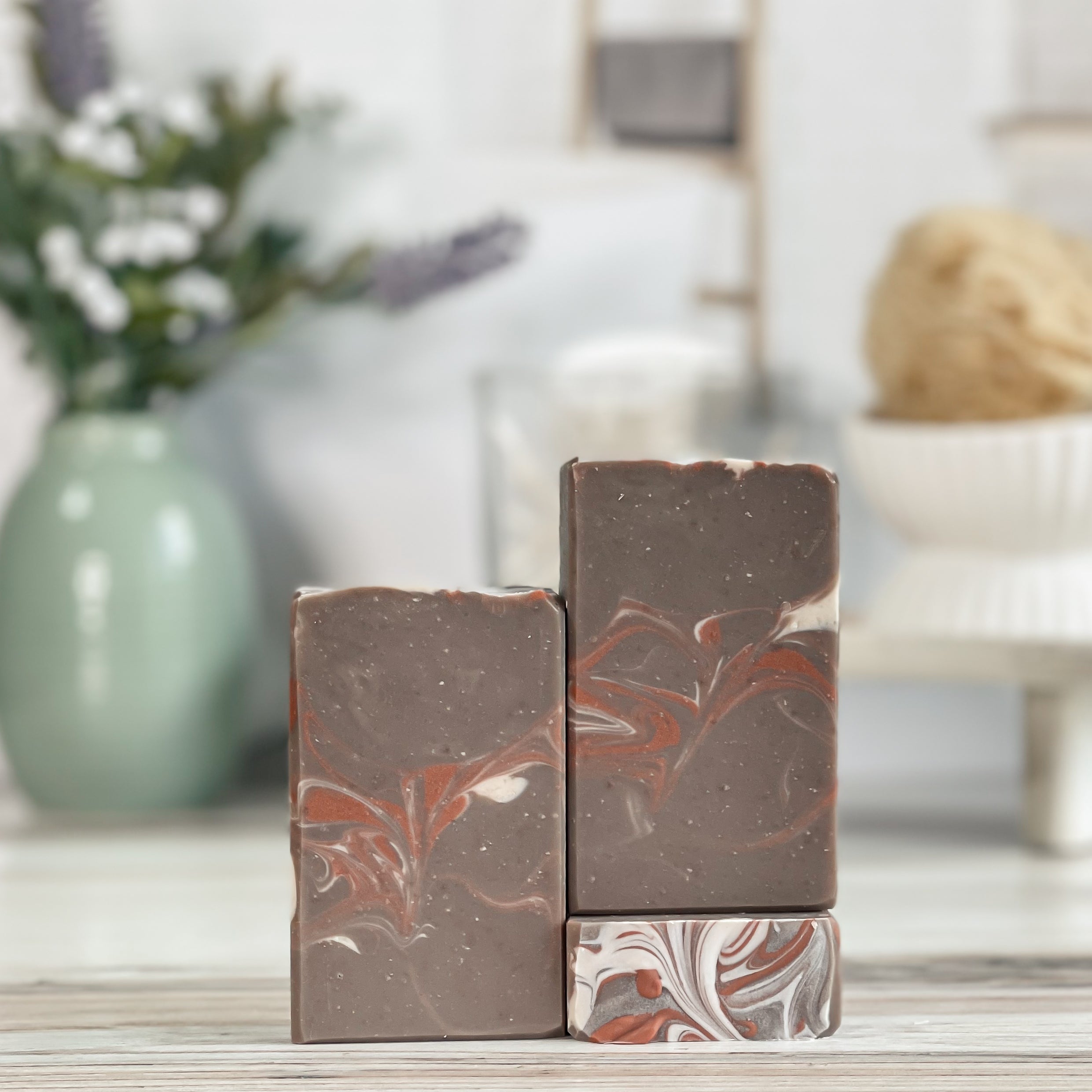 Three marbled soap bars on a wooden surface with a blurred background