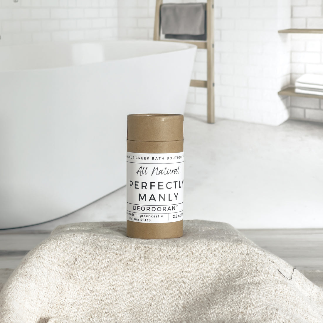 perfectly manly deodorant is shown, the label is minimalist in design, white with black lettering. in the background is a spa like bathroom