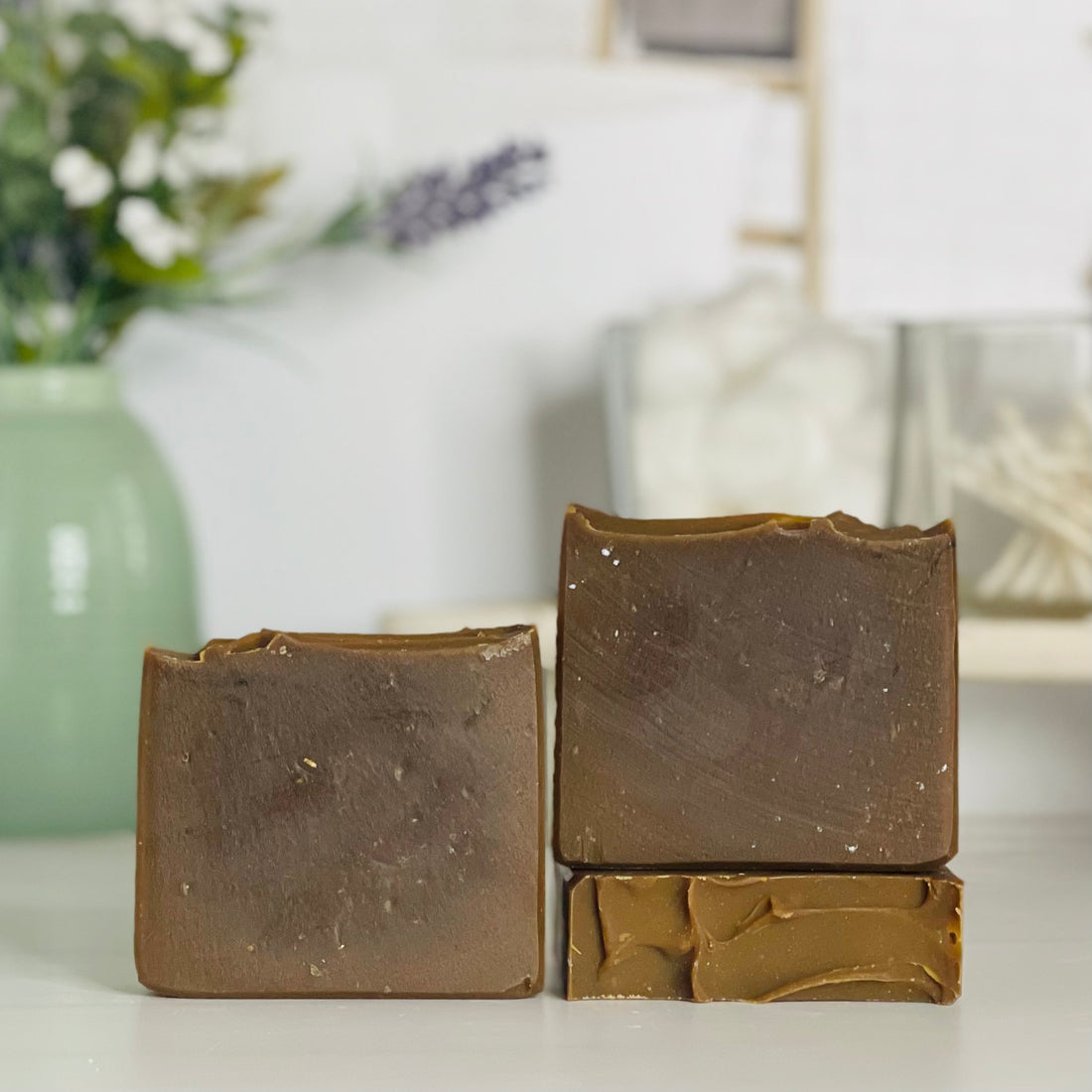 one pine tar exfoliating soap is standing next to one laying flat to show the top and another standing on the flat one to show more of the soap colors