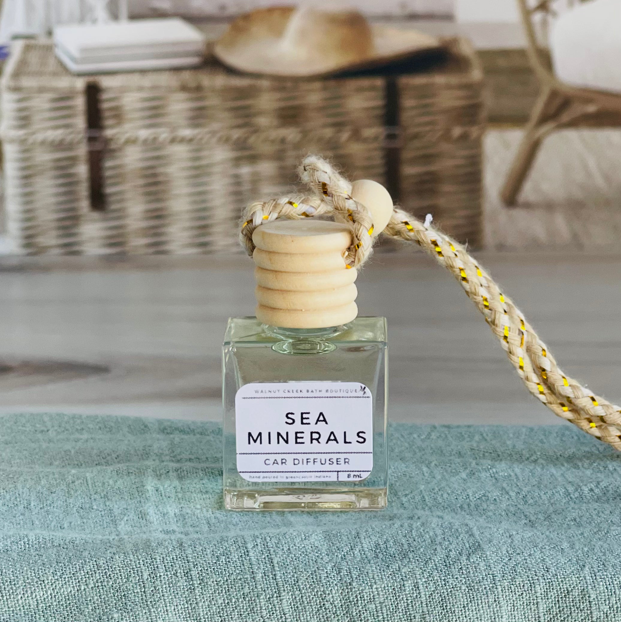 sea minerals car diffuser shown up close on a green cloth in front of a wicker basket.