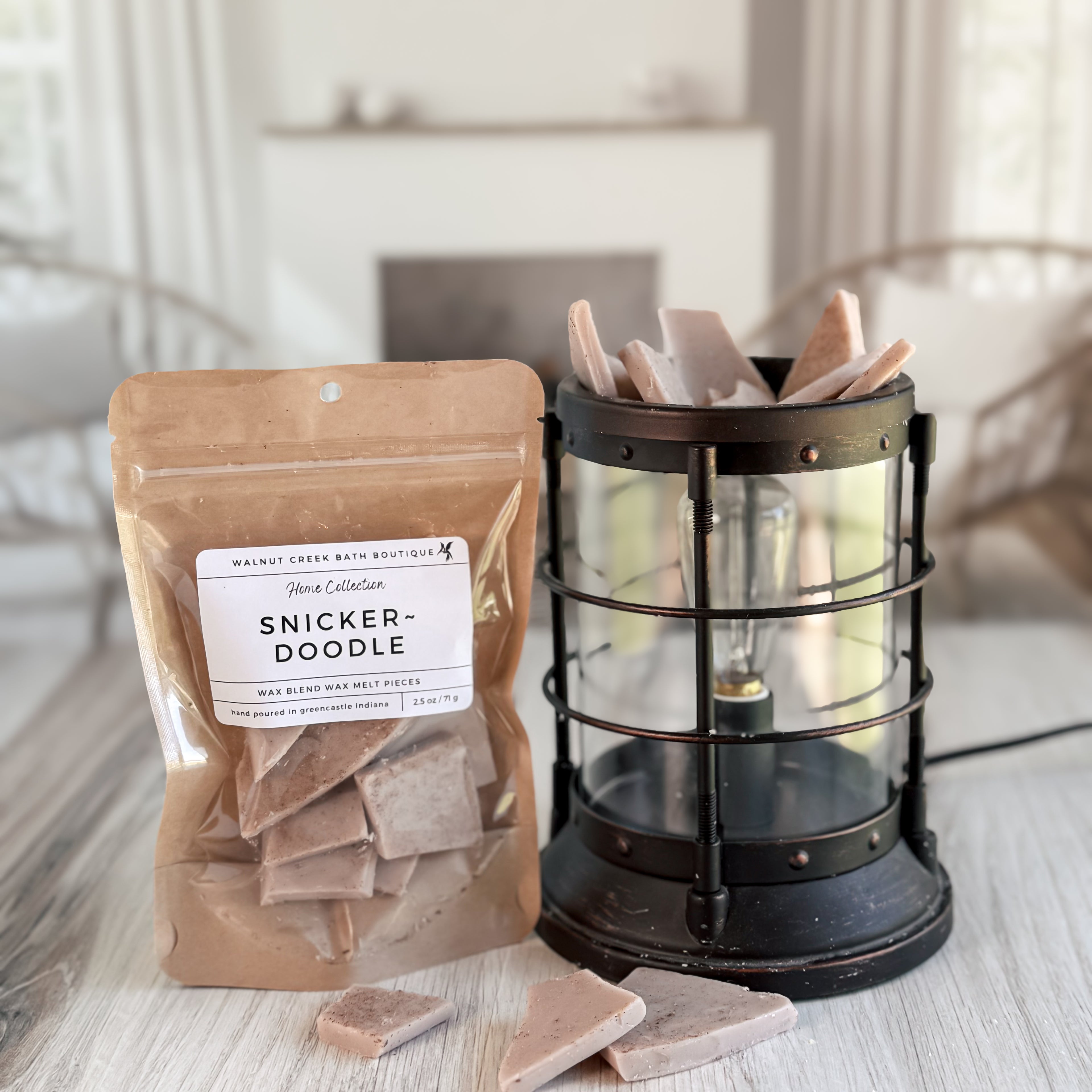 Packaged Snickerdoodle wax melts next to a decorative lantern on a wooden surface.