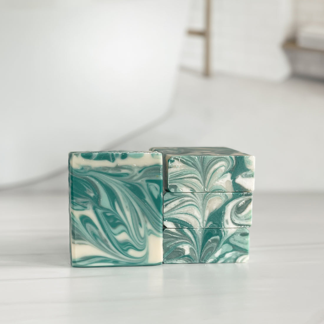 a tobacco flower soap is standing tall while 3 other soaps are tacked on top of each other to show the white and green swirls