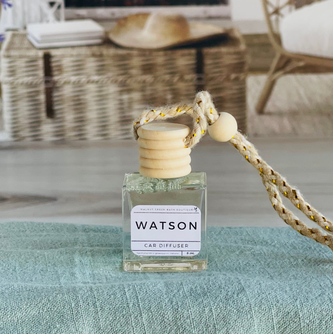 watson car diffuser shown up close on a green cloth in front of a wicker basket.
