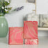 there are three vanilla kissed soaps, one laying flat to show the top and one standing tall on top of it. next to those is a third soap standing next to them showing the two pinks and the swirls. in the background is a sage green vase with some small buds.