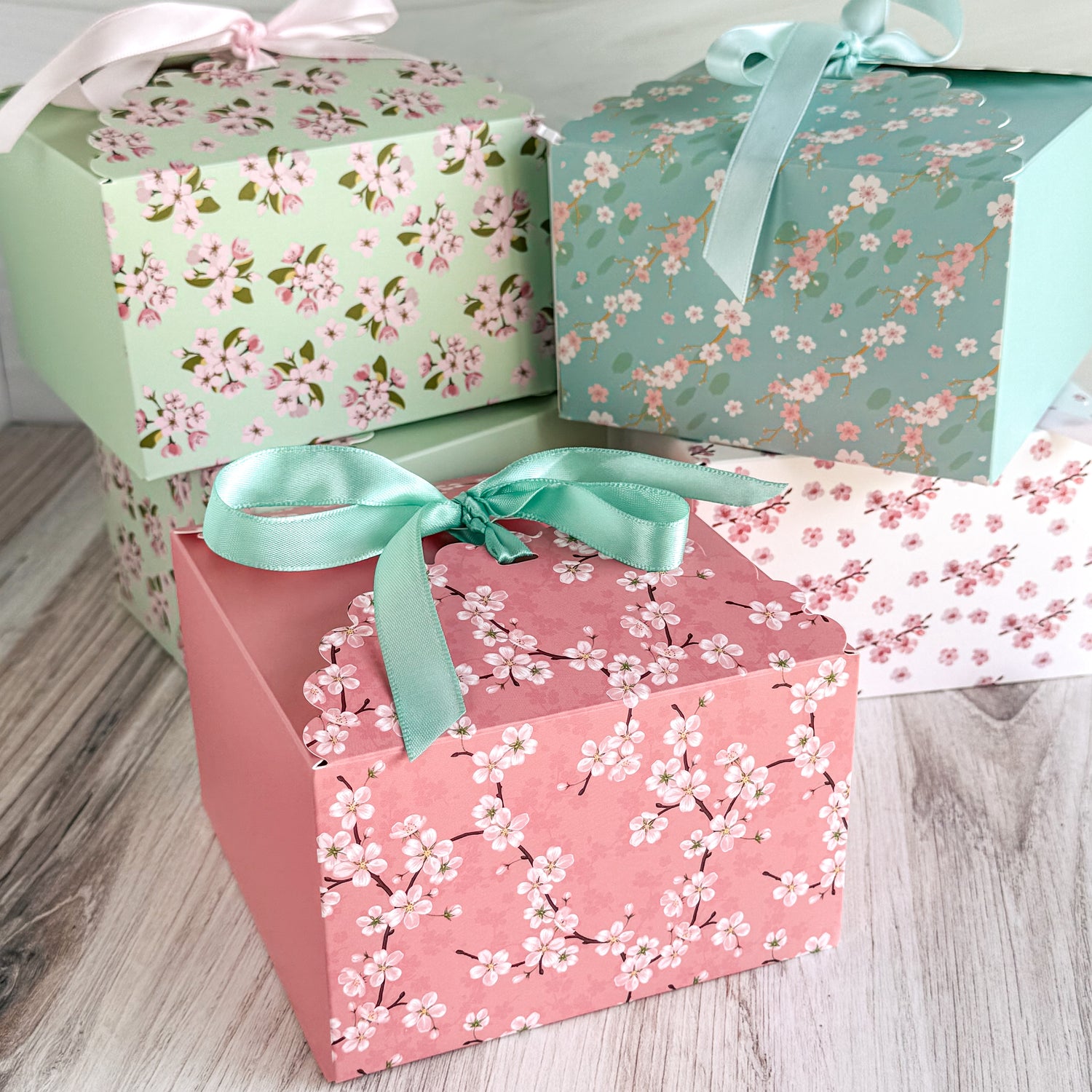 Three gift boxes with floral patterns and ribbons on a wooden surface