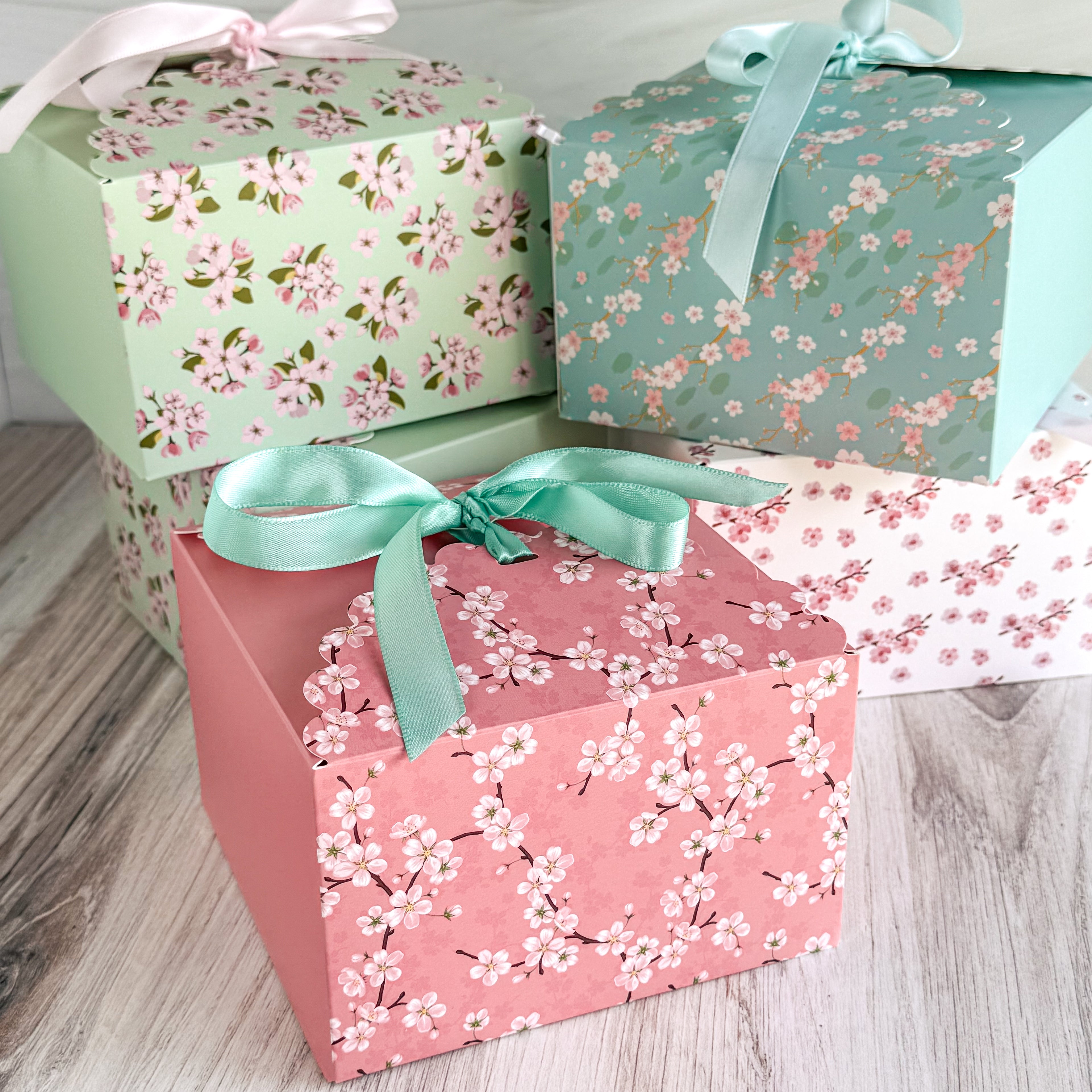 Three gift boxes with floral patterns and ribbons on a wooden surface