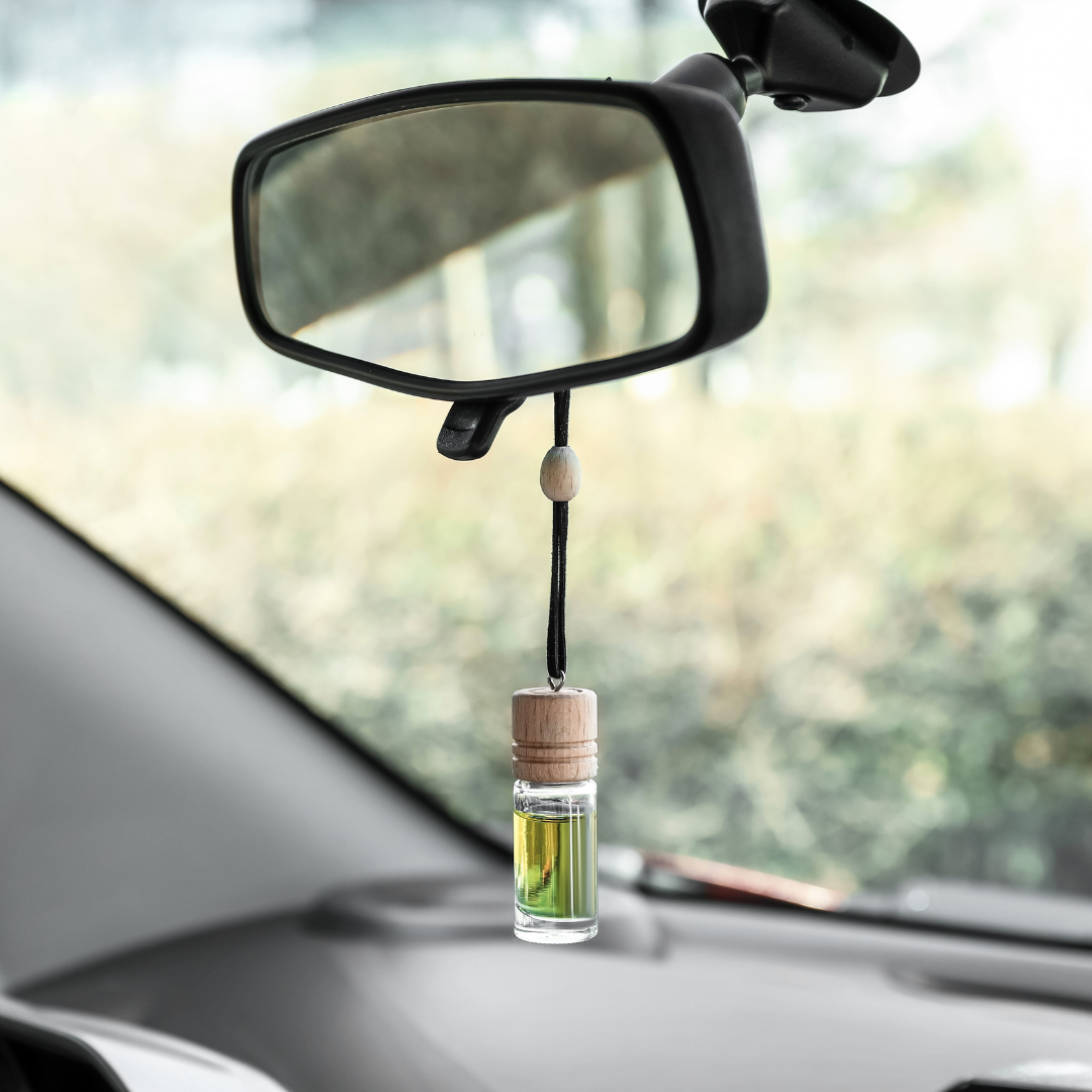 image of a clear bottle wiht amber liquid hanging from a car mirror