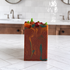 A rectangular handmade soap bar with a terracotta orange base, marbled orange and teal swirls, and small decorative pepperoni and green pepper accents on top, standing on a white tiled countertop in a kitchen setting.