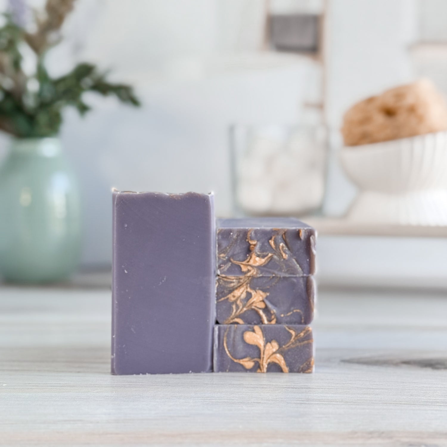3 purple soaps stacked with a pretty gold swirled design.  standing next to one standing facing you to show the simple purple soap.