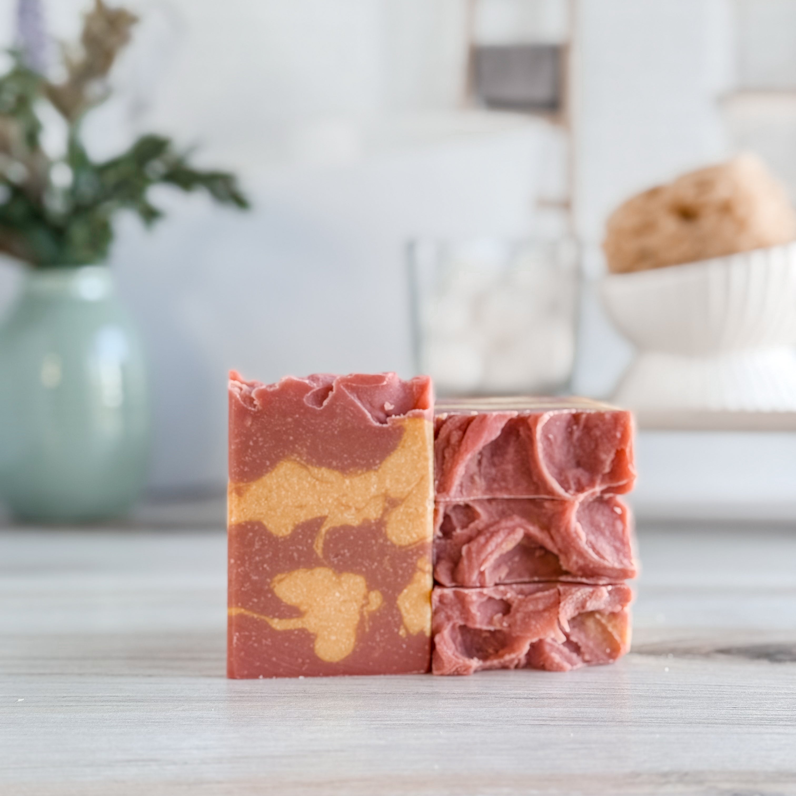 Three marbled soap bars on a wooden surface with a blurred background
