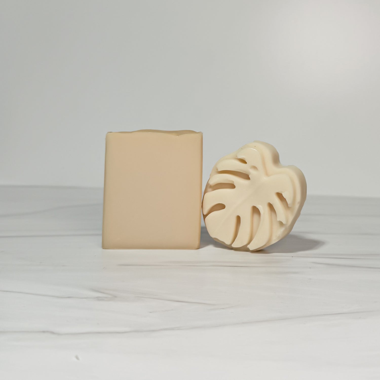 Two beige soap bars on a light gray background