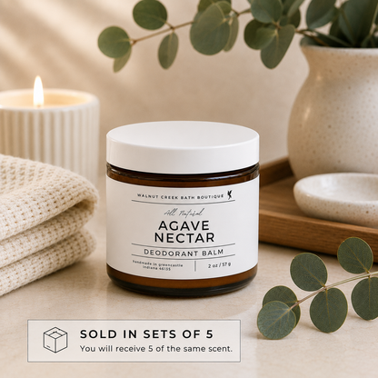 Agave Nectar deodorant balm jar with candle and eucalyptus leaves on a neutral background