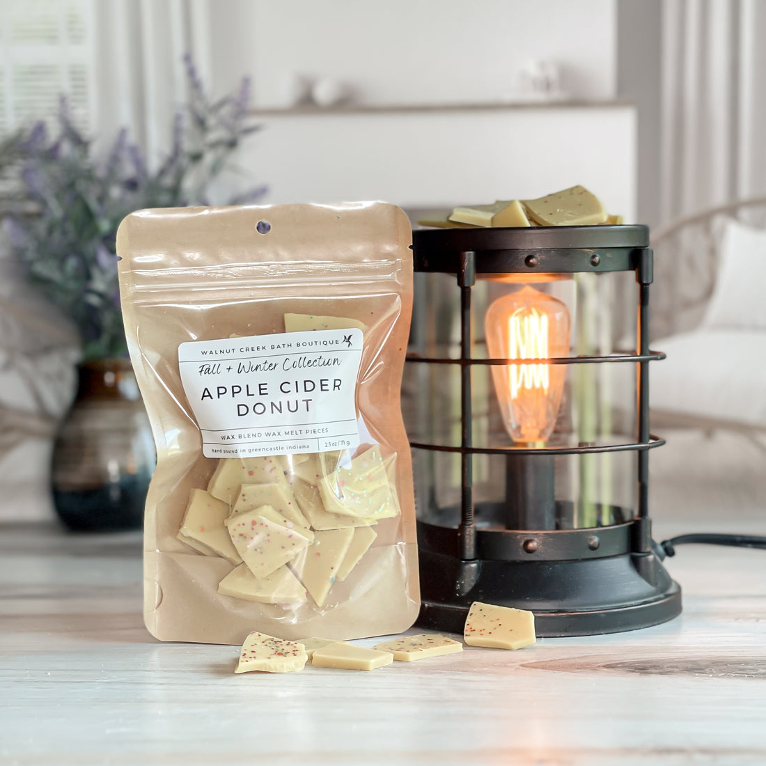 apple cider donut wax melt bag next to lit burner. there are wax melts on the table scattered about to shoe the pieces - these are  orange brittle pieces