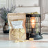 apple cider donut wax melt bag next to lit burner. there are wax melts on the table scattered about to shoe the pieces - these are  orange brittle pieces