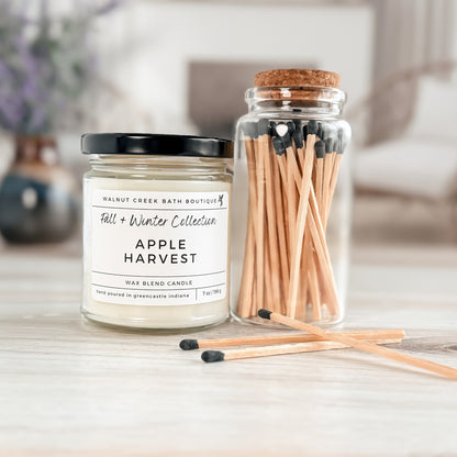 Apple Harvest candle and matches on a wooden surface with a blurred background