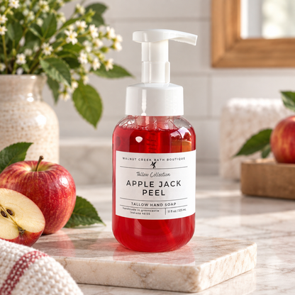 Walnut Creek Bath Boutique Yellow Collection Apple Jack Peel Yellow Hand Soap in a clear bottle with red liquid and a white pump, displayed on a marble tray with apples and flowers in the background.