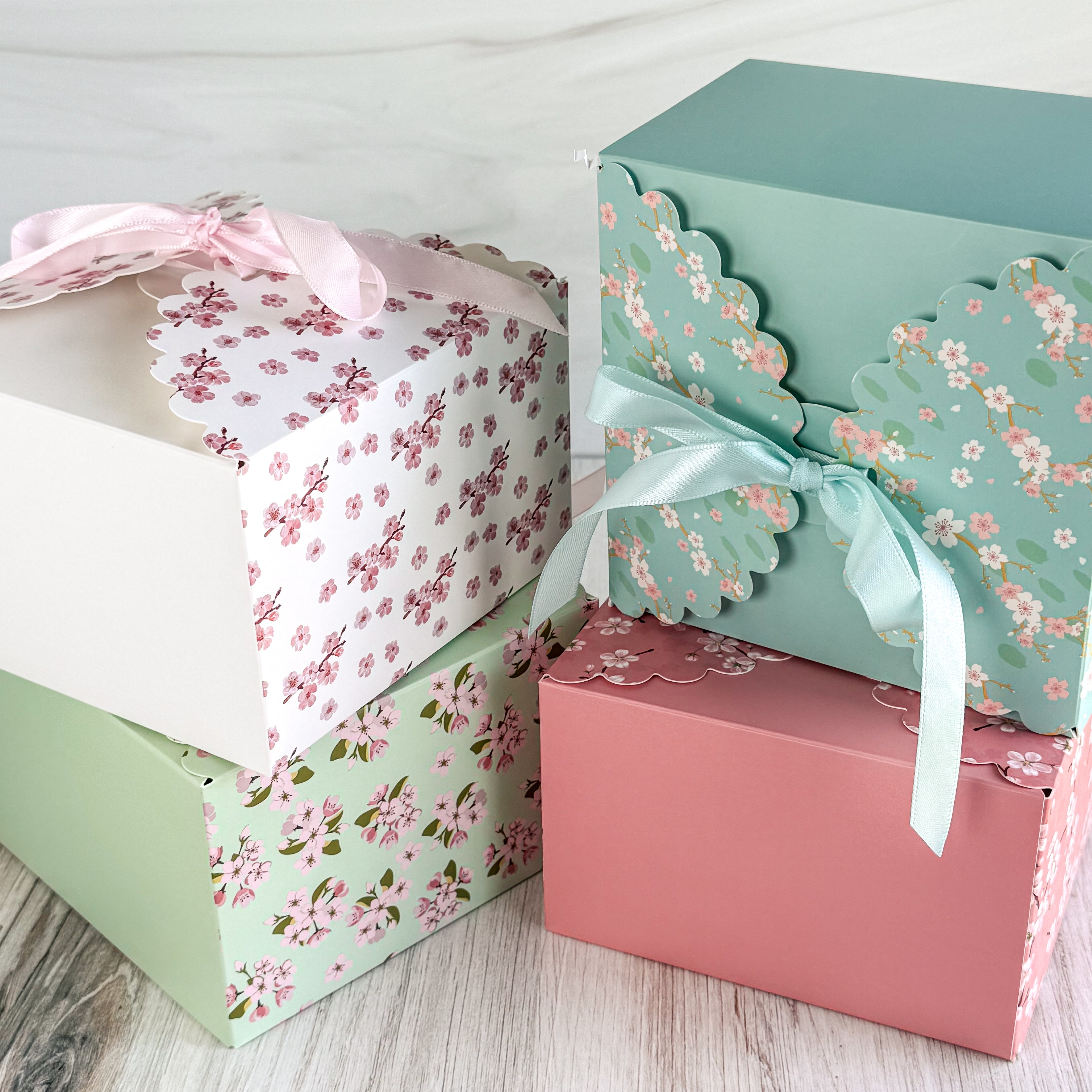 Decorative gift boxes with floral patterns and ribbons on a wooden surface.