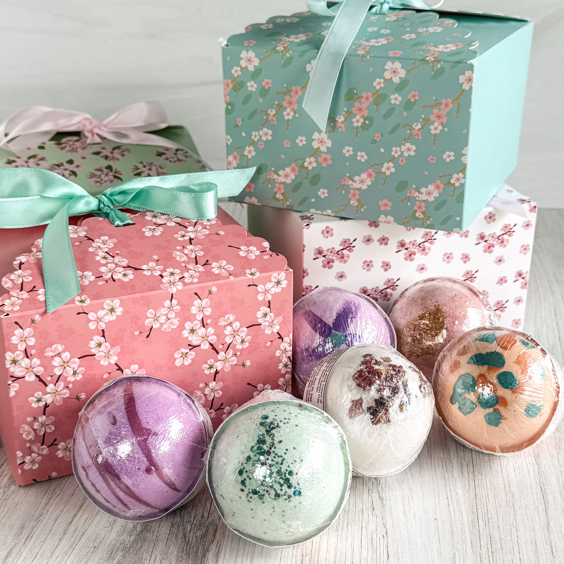 Bath bombs with floral packaging on a light wooden surface