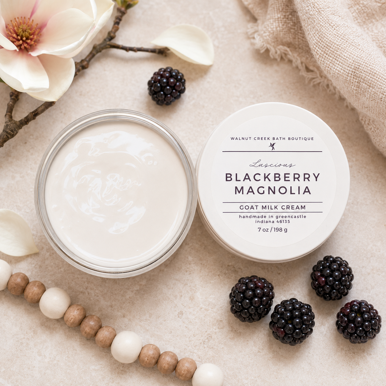 Goat milk cream jar with blackberries and flowers on a textured surface